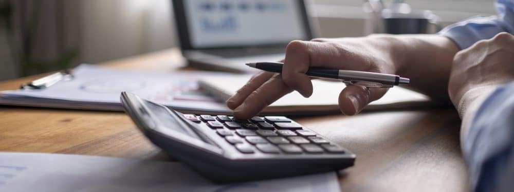 Person calculating on a calculator at a desk