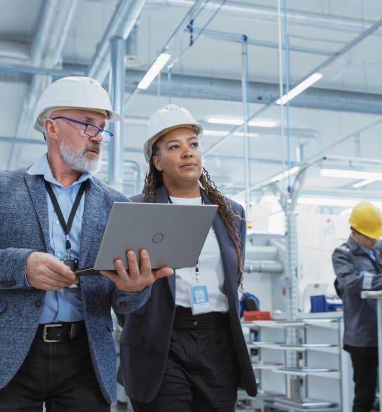 Two people in protective headgear reviewing information on a laptop